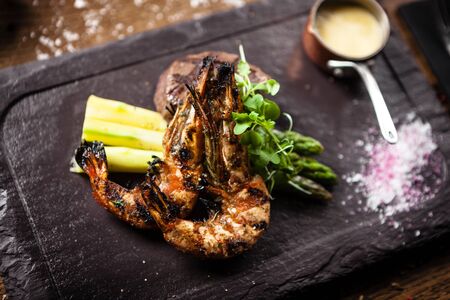 Tasting menu. Beef steak and grilled tiger prawns with asparagus and garlic sauceの写真素材