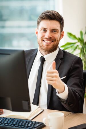 Young businessman in office sitting at his deskの写真素材