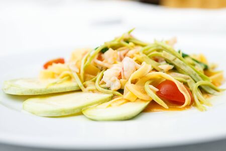 Tagliatelle with tiger prawns, tomatoes and zucchiniの写真素材
