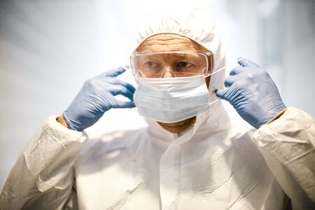 corona virus concept. male doctor putting on maskの写真素材