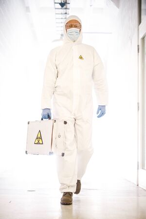 corona virus concept. male doctor waliking in coridor with biohazard caseの写真素材