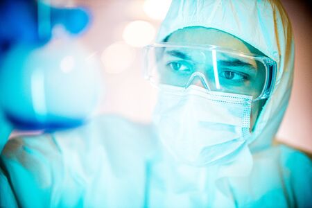 corona virus concept. male doctor reviewing glass flaskの写真素材