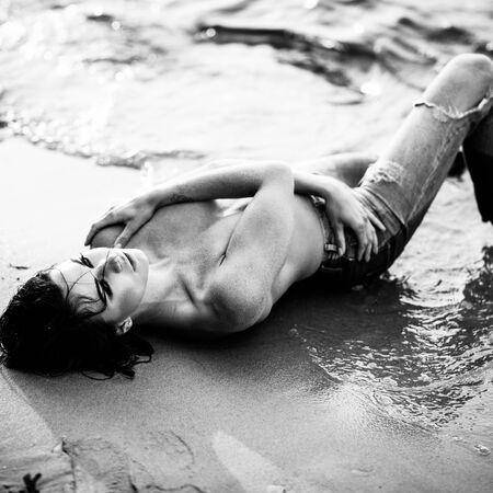 Beautiful lady in black swimsuit lies on a sandy beachの写真素材