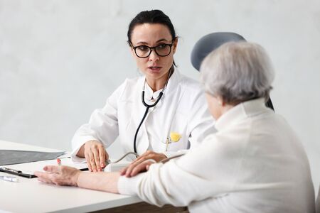 healthcare in hospital. female doctor with clipboard consulting senior lady patient after treatment in medical clinic cabinetの写真素材
