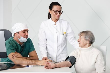 healthcare in hospital. male surgeon and female doctor or nurse consulting senior lady patient in medical clinic cabinetの写真素材