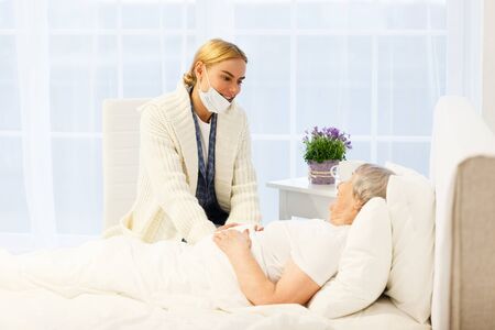 healthcare in hospital. daughter or female relative visiting senior lady lying in bed while getting treatment at medical clinic wardの写真素材