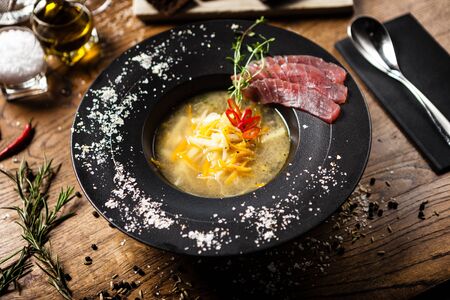 Clear Fish soup served with slices of tuna in a bowl. Delicious healthy Italian traditional food closeup served for lunch on a table in modern gourmet cuisine restaurant.の写真素材
