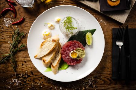 Tuna tartare: Guacamole quail egg baguette on a plate. Delicious healthy raw food closeup served for lunch on a table in modern gourmet cuisine restaurant.の写真素材