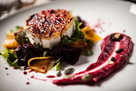 Grilled goat cheese salad Pickled beetroot pumkin, cranberry jam, pumkin seeds Delicious mediterranean traditional vegeterian food closeup served for lunch in modern cuisine gourmet restaurantの写真素材