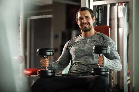 Fitness in gym, sport and healthy lifestyle concept. Handsome athletic man in grey shirt making...