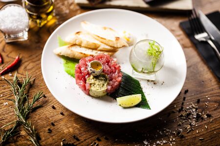 Tuna tartare: Guacamole quail egg baguette on a plate. Delicious healthy raw food closeup served for lunch on a table in modern gourmet cuisine restaurant.の写真素材