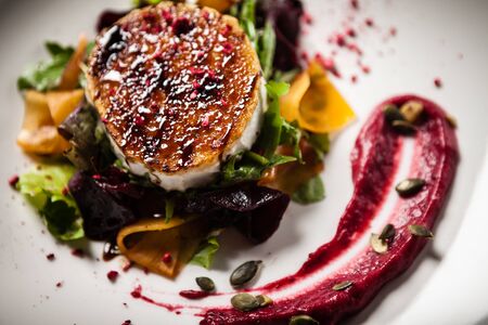 Grilled goat cheese salad Pickled beetroot pumkin, cranberry jam, pumkin seeds Delicious healthy mediterranean traditional vegeterian food closeup served for lunch in modern cuisine gourmet restaurantの写真素材