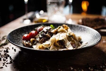 Black Angus pappardelle pasta with beef, champignon and parmegano cheese on a black plate. Delicious healthy mediterranean traditional food closeup served on a table for lunch in modern cuisine gourmet restaurant.の写真素材