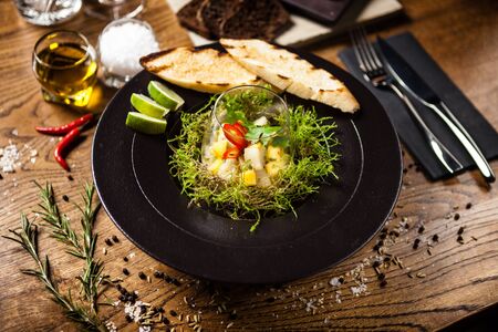 Scallop ceviche with mango, chilli and cilantro served with liquid ice smoke in a plate. Delicious healthy food closeup served for lunch on a table in modern gourmet cuisine restaurant.の写真素材