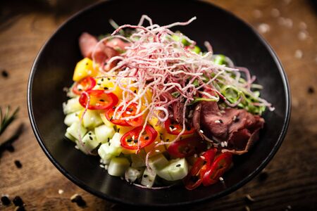 Poke with beef: Glass noodle, avocado, edamame and mango in a bowl. Delicious healthy food closeup served for lunch on a table in modern gourmet cuisine restaurant.の写真素材