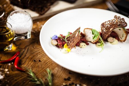 Steak tartare: Horseradish creme, black bread and baguette chips on a plate. Delicious healthy food closeup served for lunch on a table in modern gourmet cuisine restaurantの写真素材