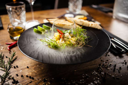 Scallop ceviche with mango, chilli and cilantro served with liquid ice smoke in a plate. Delicious healthy food closeup served for lunch on a table in modern gourmet cuisine restaurantの写真素材