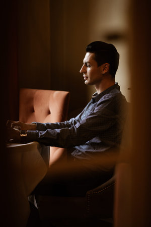 LGBTQ community lifestyle concept. Young homosexual man sits at the table in old-fashioned city...