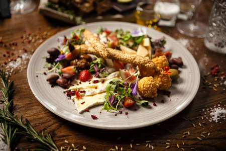 Cheese platter for two: Goat cheese cream, gorgonzola, camembert, grissini and fig jam. Delicious healthy Italian traditional food closeup served for lunch in modern gourmet cuisine restaurantの写真素材