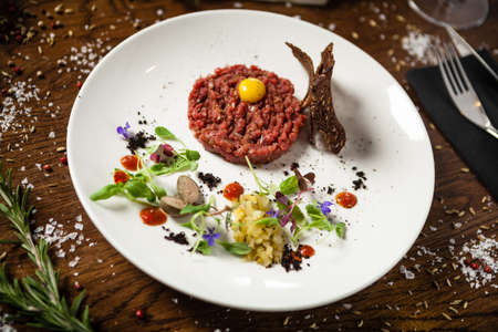 Steak tartare. Horseradish creme, black bread, baguette chips on white plate. Delicious healthy raw meat food closeup served on a table for lunch in modern cuisine gourmet restaurant.の写真素材