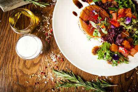 Goat cheese salad. Strawberry-melon salad with chilli, apple-orange sauce, fig jam on white plate. Delicious meat food closeup served on a table for lunch in modern cuisine gourmet restaurantの写真素材