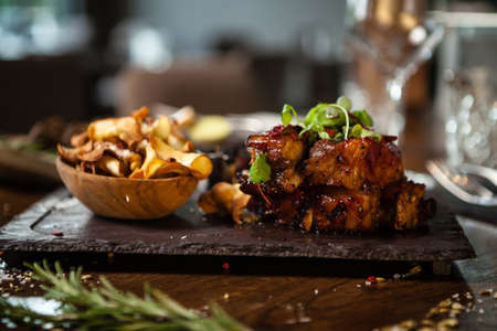Pork ribs cooked at low temperature. Blackcurrant sauce, parsnip chips with Parmesan cheese. Delicious healthy meat food closeup served on a table for lunch in modern cuisine gourmet restaurantの写真素材