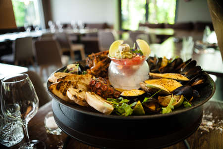 Seafood platter for 2-4 persons. Octopus, blue mussels, cooked green mussels, grilled tiger prawns, tuna tartare. Delicious seafood closeup served on a table for lunch in modern gourmet restaurantの写真素材