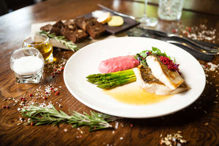 Pike-perch fillet. Asparagus, pearl couscous, white wine sauce, beet-flavored mashed potatoes. Delicious seafood fish closeup served on a table for lunch in modern cuisine gourmet restaurantの写真素材