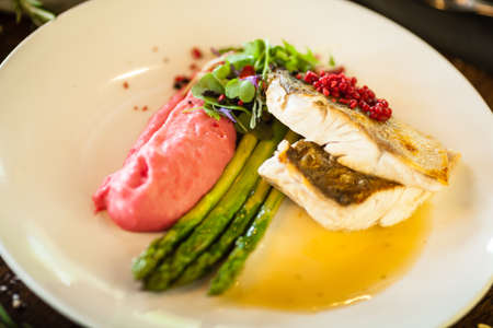 Pike-perch fillet. Asparagus, pearl couscous, white wine sauce, beet-flavored mashed potatoes. Delicious seafood fish closeup served on a table for lunch in modern cuisine gourmet restaurantの写真素材