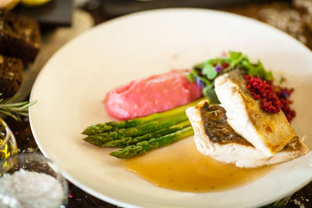 Pike-perch fillet. Asparagus, pearl couscous, white wine sauce, beet-flavored mashed potatoes. Delicious seafood fish closeup served on a table for lunch in modern cuisine gourmet restaurantの写真素材