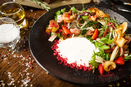 Crudo ham salad. Stracciatella and Grana Padano cheese, sundried tomato, fresh cucumber. Delicious healthy mixed greens food closeup served on a table for lunch in modern cuisine gourmet restaurant.の写真素材