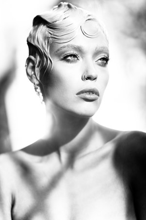 Beauty portrait of young attractive fashion model with short wet blond hair. Fresh, clean skin. Blue eyes, professional makeup. Black and white, monochrome. Natural sunlight and shadows indoors.の写真素材