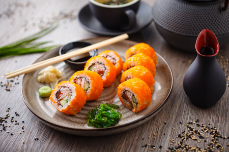 Sushi maki rolls California Futomaki with salmon, avocado, cucumber, crab and flying fish roe on a plate with chopsticks, soy sauce, wasabi and ginger. Japanese traditional seafood served restaurant.の写真素材