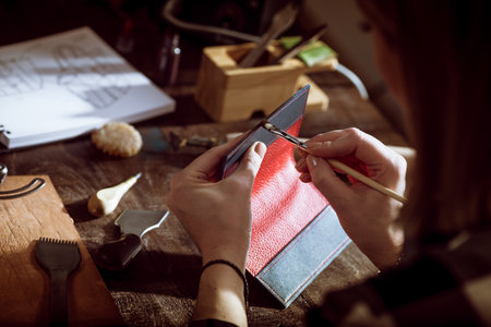 Leather handbag craftsman at work in a vintage workshop. Small business concept.の写真素材