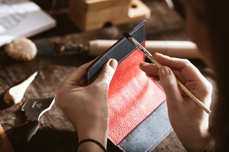Leather handbag craftsman at work in a vintage workshop. Small business concept.の写真素材