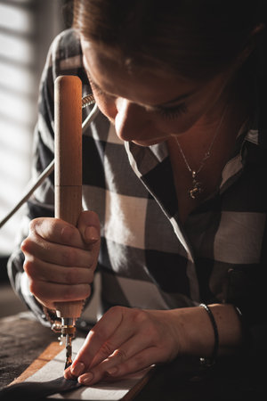 Leather handbag craftsman at work in a vintage workshop. Small business concept.の写真素材