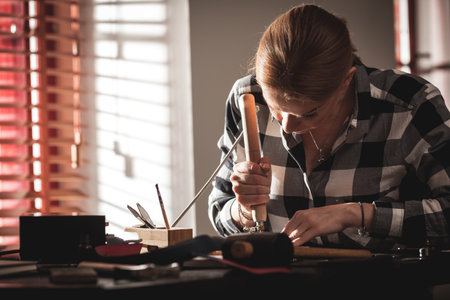 Leather handbag craftsman at work in a vintage workshop. Small business concept.の写真素材