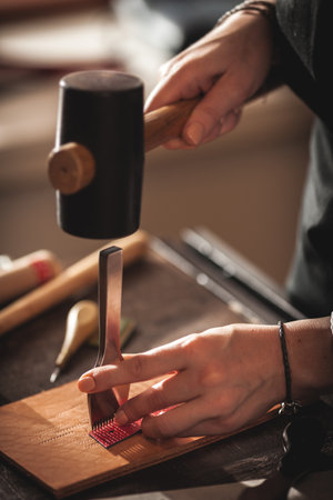 Leather handbag craftsman at work in a vintage workshop. Small business concept.の写真素材