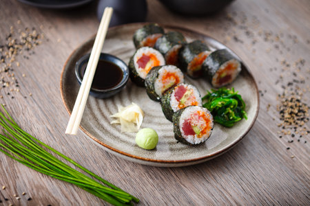 Sushi maki rolls with tuna, flying fish caviar, crab, avocado on a plate with chopsticks, soy sauce, wasabi and ginger. Japanese traditional food closeup served for lunch in modern gourmet restaurant.の写真素材