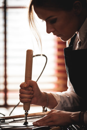 Leather handbag craftsman at work in a vintage workshop. Small business concept.の写真素材