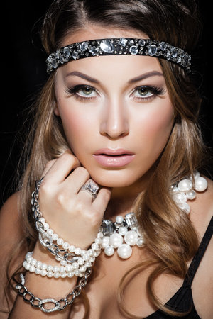 Perfect beauty and jewelry concept. Portrait of beautiful female model wearing ring, necklace and wristband on black background. Young blond woman shows glamorous finery.の写真素材