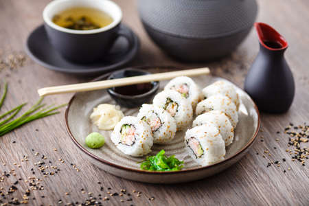 Sushi maki rolls California with crab, cucumber and avocado on a plate with chopsticks, soy sauce, wasabi and ginger. Japanese traditional seafood served for lunch in modern gourmet restaurant.の写真素材