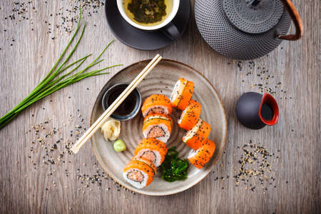 Sushi maki rolls with spicy crab, salmon, cucumber on a plate with chopsticks, soy sauce, wasabi and ginger. Japanese traditional seafood served for lunch in modern gourmet restaurant.の写真素材
