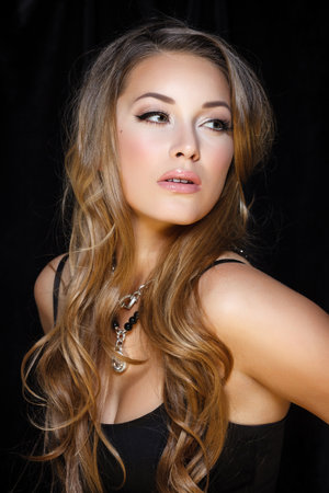Perfect beauty and jewelry concept. Portrait of beautiful female model wearing ring, necklace and wristband on black background. Young blond woman shows glamorous finery.の写真素材