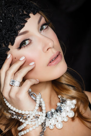 Perfect beauty and jewelry concept. Portrait of beautiful female model wearing ring, necklace and wristband on black background. Young blond woman shows glamorous finery.の写真素材
