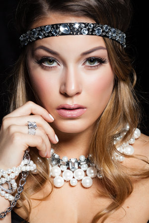 Perfect beauty and jewelry concept. Portrait of beautiful female model wearing ring, necklace and wristband on black background. Young blond woman shows glamorous fineryの写真素材