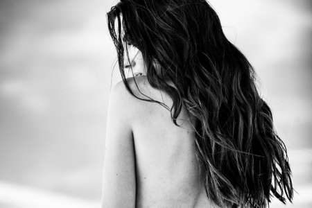 Summertime recreation concept. Beautiful young sexy woman with closeup portrait on a beach. Fashion female model face near the sea. Black and white monochromeの写真素材