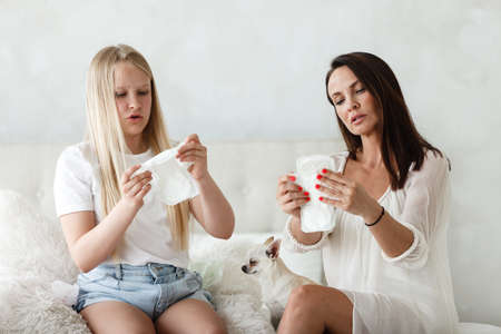 Woman hygene concept. Periods. Menstrual cycle. Mother explains daughter how to use hygiene pads and tampons. Woman and teenage girl talking at home.の写真素材