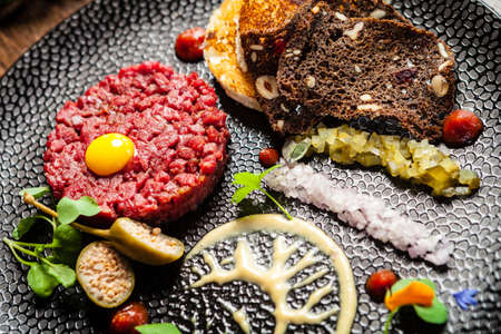 Beef tartare from Black Angus. Onion, quail egg, tomato sauce, mustard mayonnaise. Delicious healthy Italian traditional food closeup served for lunch in modern gourmet cuisine restaurant.の写真素材