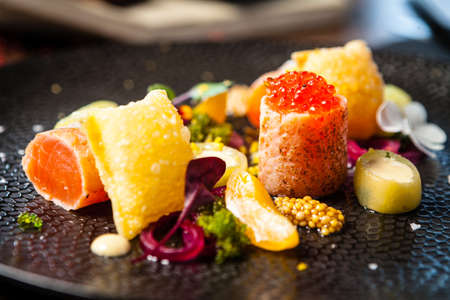 Salted Scottish salmon with trout roe. Marinated cucumber and onion, wonton chips. Delicious healthy Italian traditional food closeup served for lunch in modern gourmet cuisine restaurantの写真素材